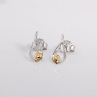 Stud earrings with a butterfly clasp. the earring  is rhodium plated silver with gold vermeil detail surrounding one set diamond.