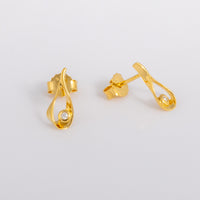 Gold vermeil stud earrings that feature a tear drop shape, detailed in a set diamond. The earrinsg have butterfly backs. One earring faces the lens and the other points off to the right.