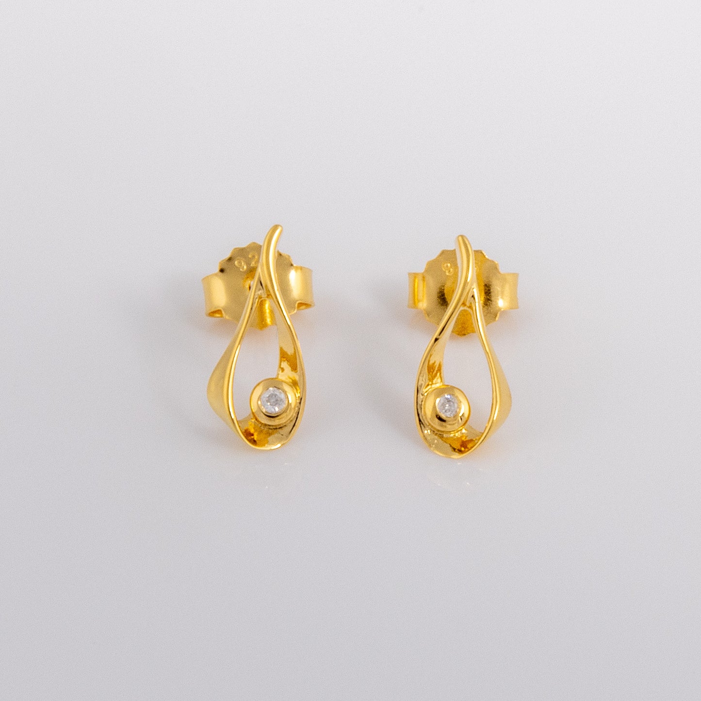 Gold vermeil stud earrings that have a teardrop design with a set diamond detail. the earrings have a butterfly clasp and are photographed on a white background