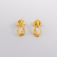 Gold vermeil stud earrings that have a teardrop design with a set diamond detail. the earrings have a butterfly clasp and are photographed on a white background
