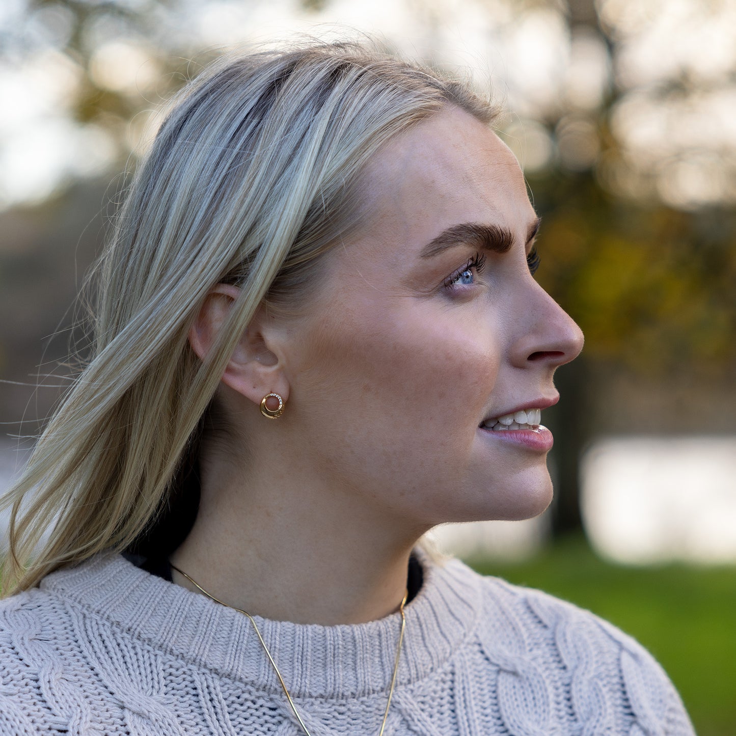 Model turning her face to the side to show gold Vermeil Circle Stud Earrings with White Cubic Zirconia. The earrings sparkle in the light.