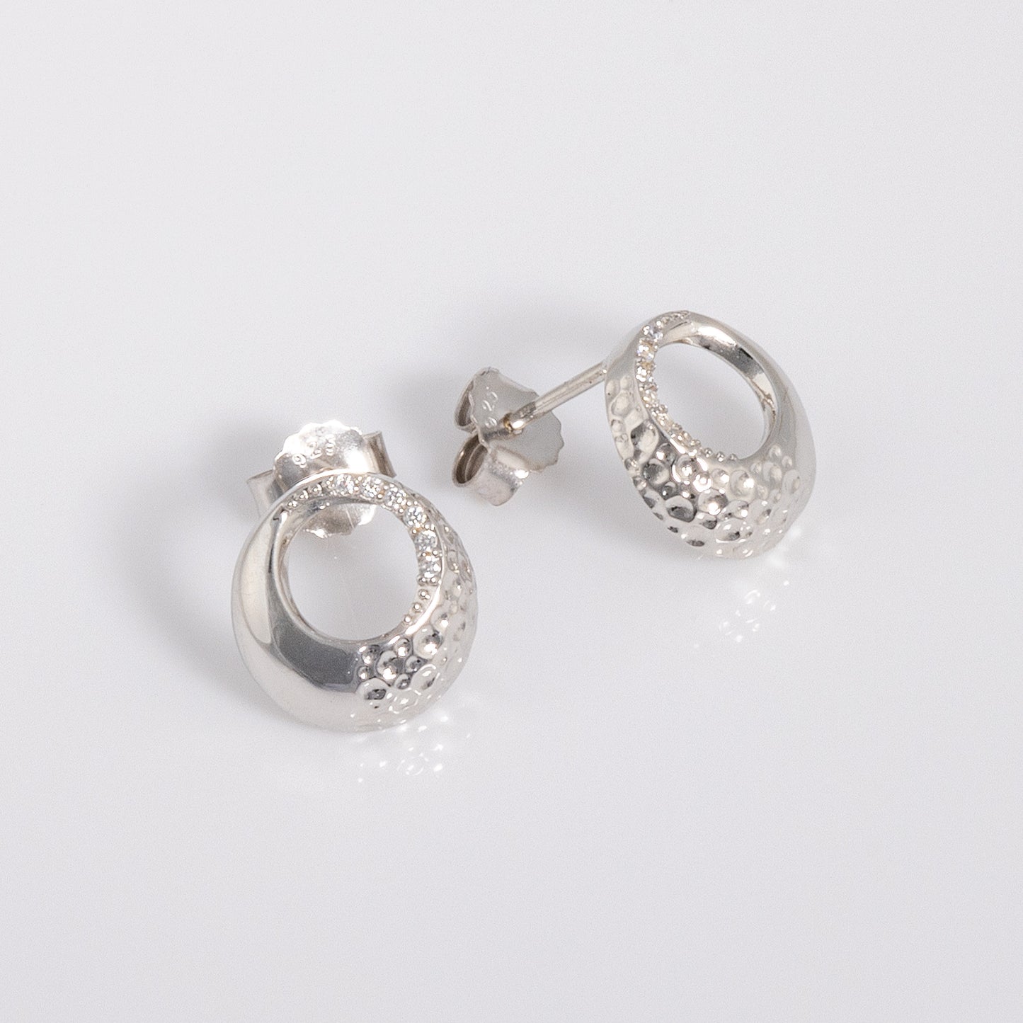 Rhodium plated silver Circle Stud Earrings with White Cubic Zirconia with a textured surface. The earrings have a butterfly back and are hypoallergenic suitable for all skin types.