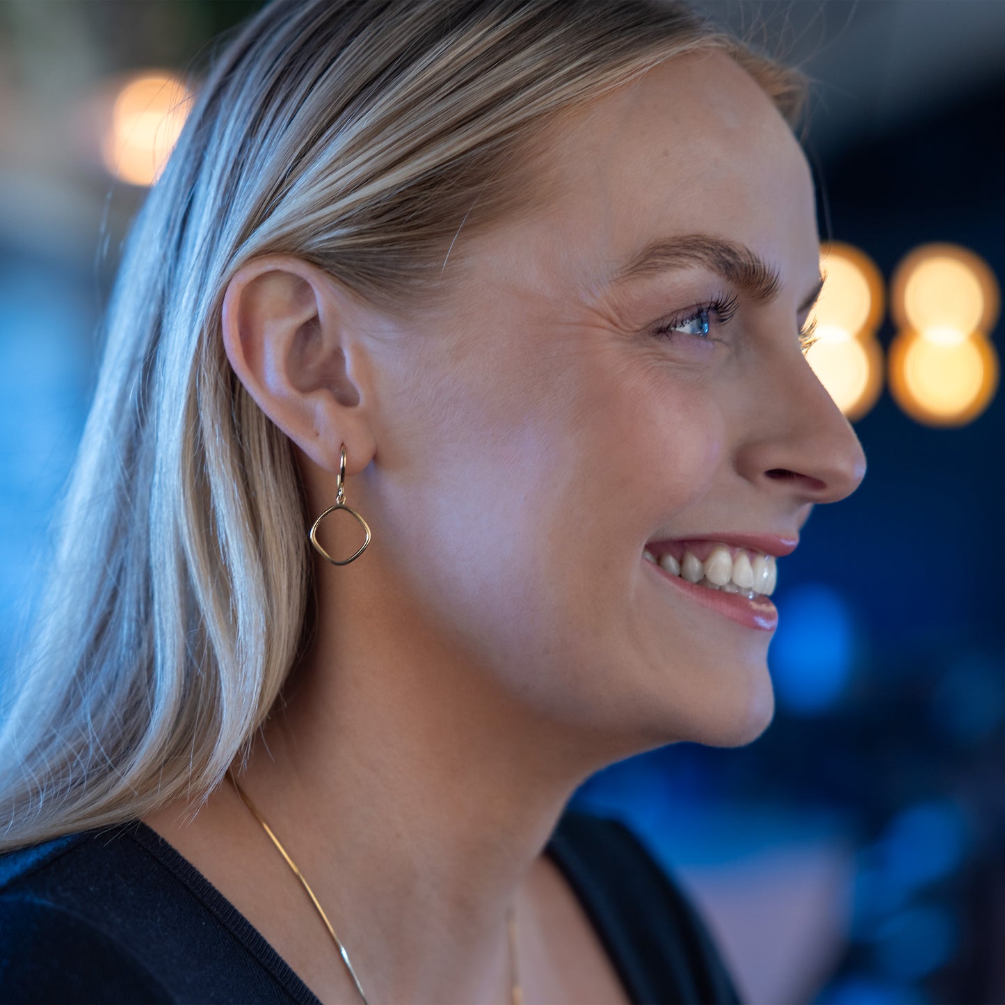 Model smiling wearing Simple Gold Vermeil Hook Earrings.
