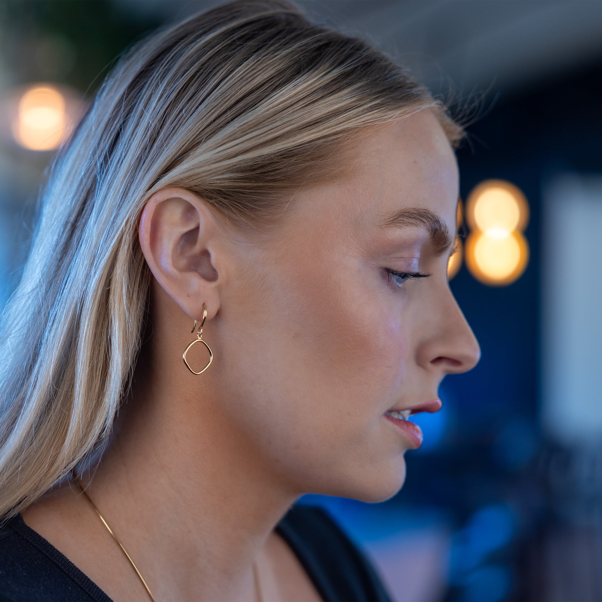 Side shot of model wearing Simple Gold Vermeil Hook Earrings. A geometric ring shape dangles from the earring.