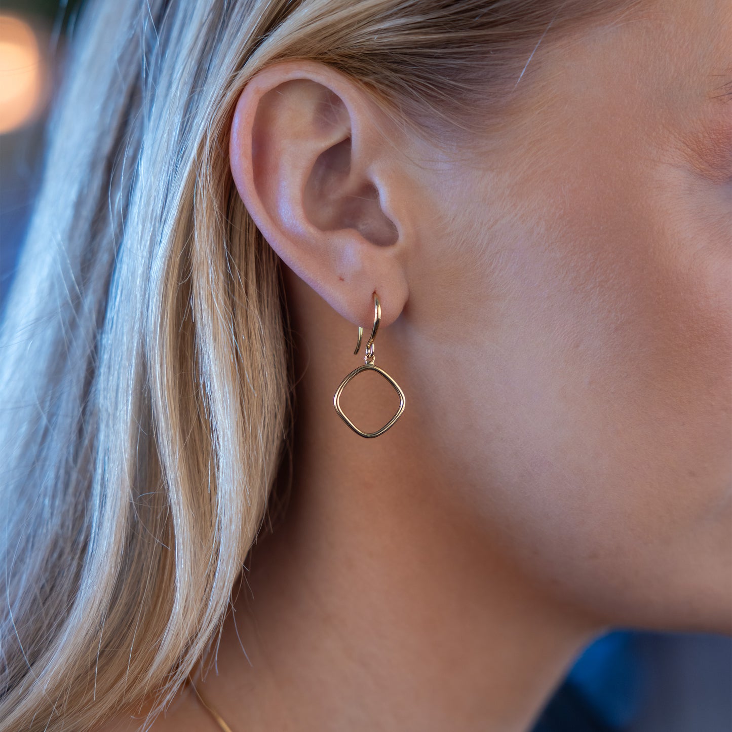 Model wearing simple Gold Vermeil Hook Earrings. The earrings feature a hanging geometric ring shape.