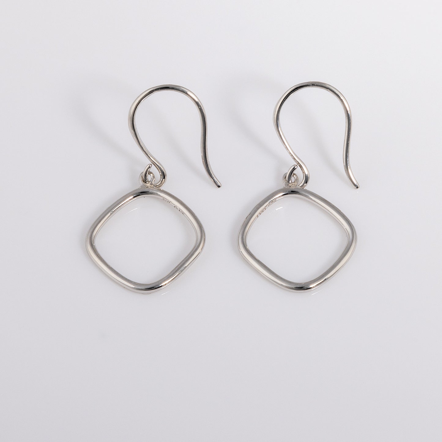 Simple rhodium plated silver Hook Earrings that have a rounded geometric shape.