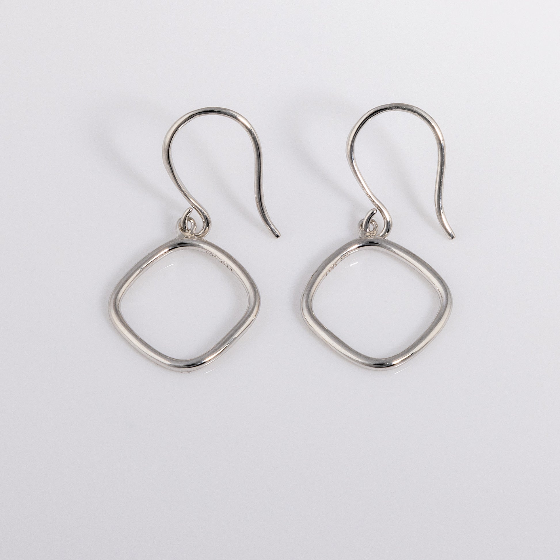 Simple rhodium plated silver Hook Earrings that have a rounded geometric shape.