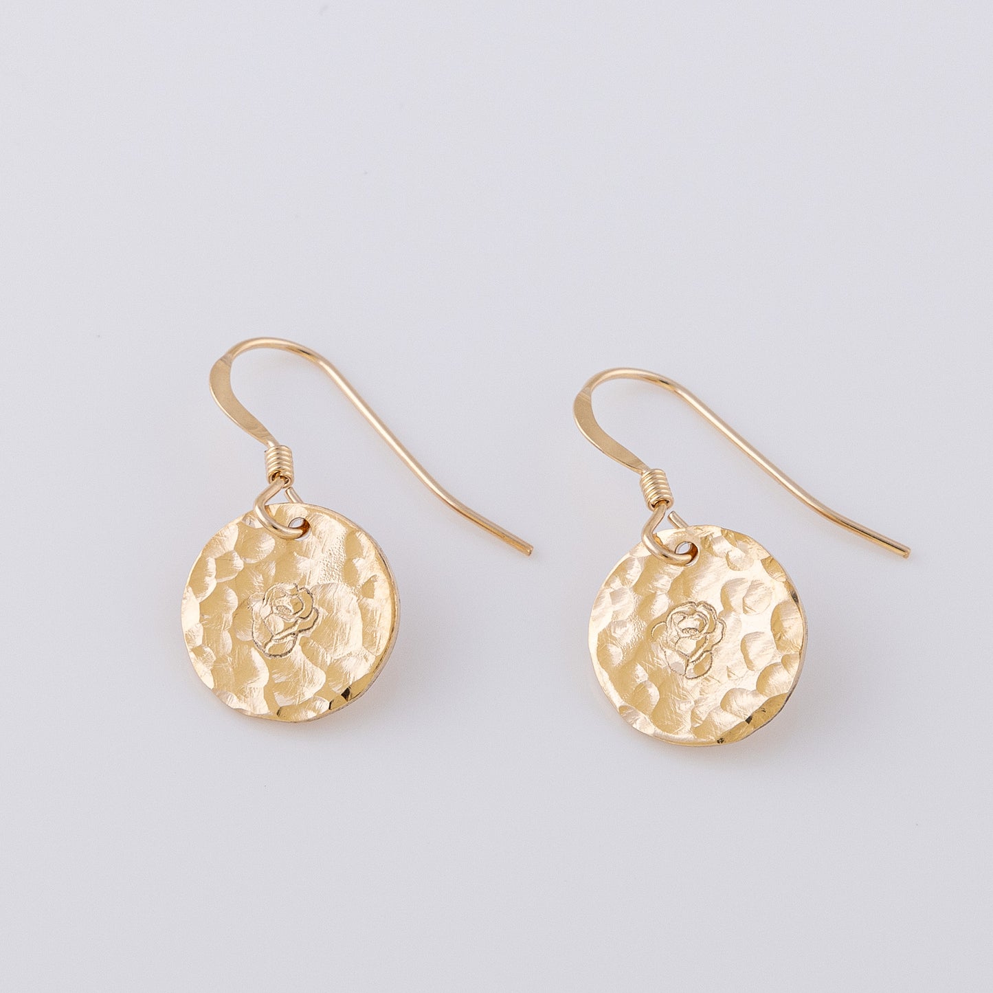 14ct gold-fill fish hook earrings. Two 14ct gold-fill disc earrings hand stamped with a rose, Junes birth flower. The discs have a hammered finish, which creates a gorgeous sparkle in the light.