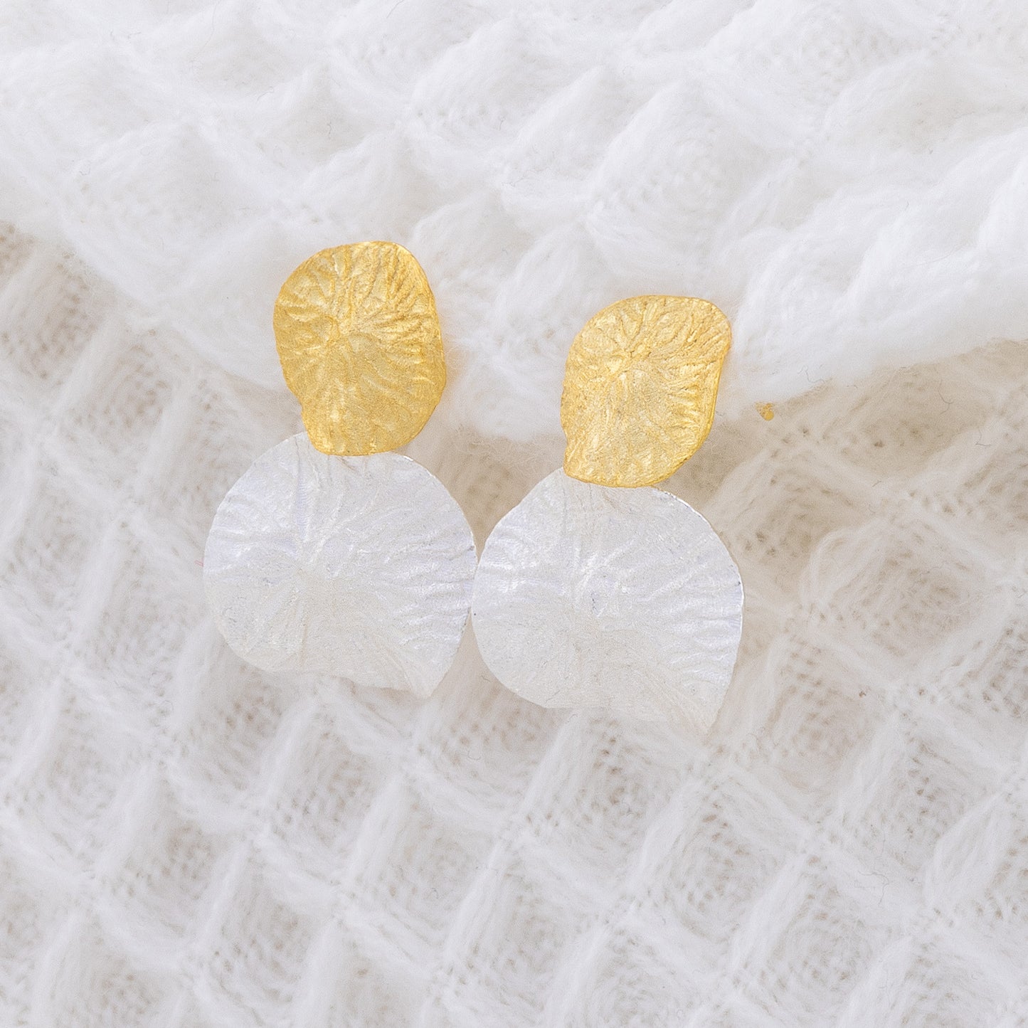Textured, mixed metal, statement earrings. The earrings are two leaf like textured discs, stacked on each other. The top disc is gold vermeil while the buttom is rhodium plated silver