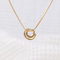Close up of a gold vermeil circle shaped pendant necklace with white cubic zirconia detail on a delicate snake chain. White background on image