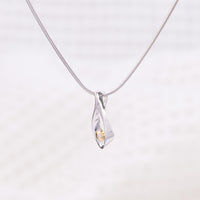 Side angle of a rhodium plated silver, snake chain, pendant necklace. The tear drop pendant is rhodium plated silver with gold vermeil detail surrounding a single set diamond.