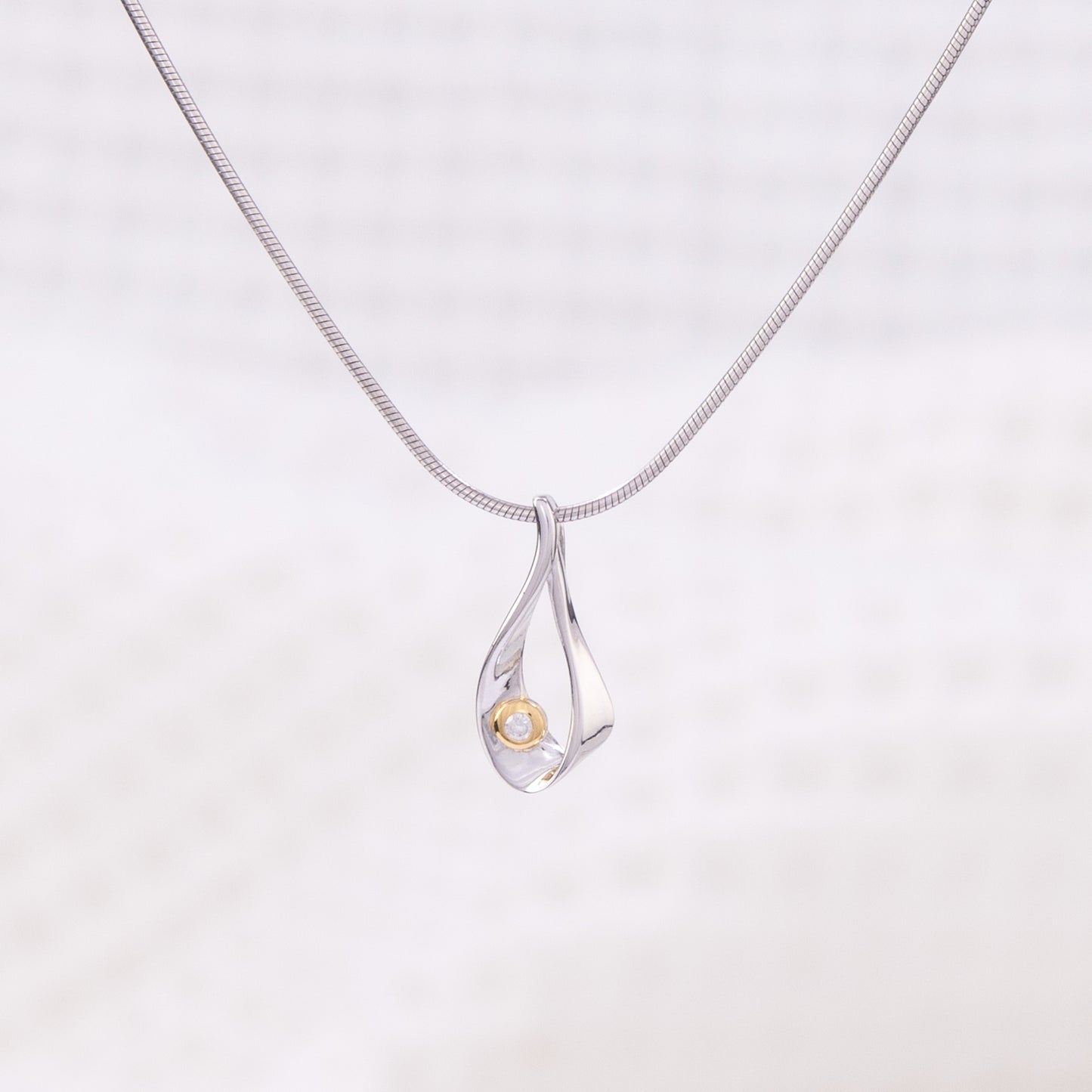 Rhodium plated silver, snake chain, pendant necklace. The tear shaped pendant is rhodium plated silver with gold vermeil detail and a set diamond