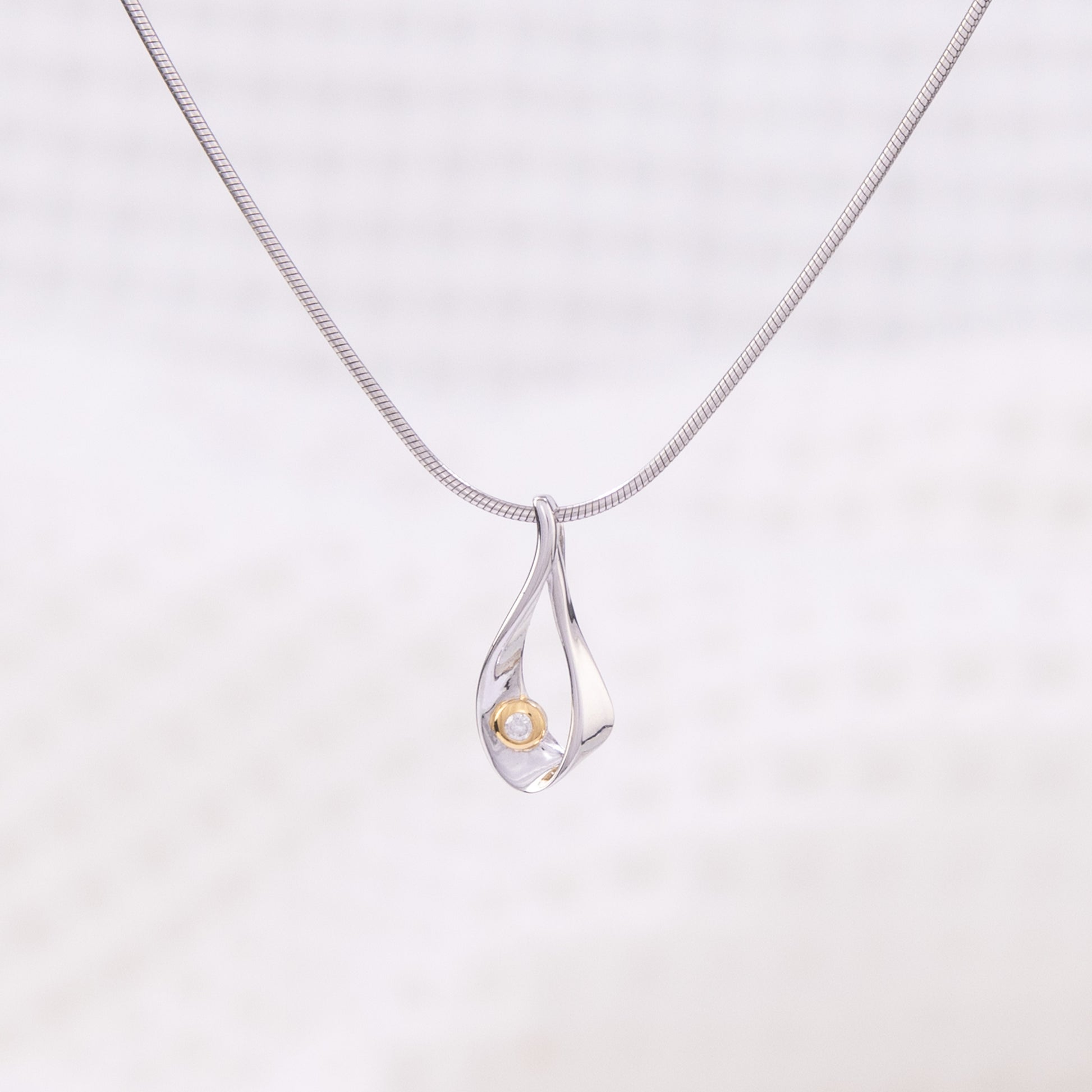 Rhodium plated silver, snake chain,  pendant necklace. The tear shaped pendant is rhodium plated silver with gold vermeil detail and a set diamond