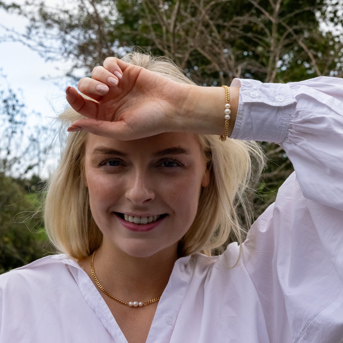 Model wearing a curb chain Gold Vermeil Necklace with a centerpiece of three Freshwater Pearls.