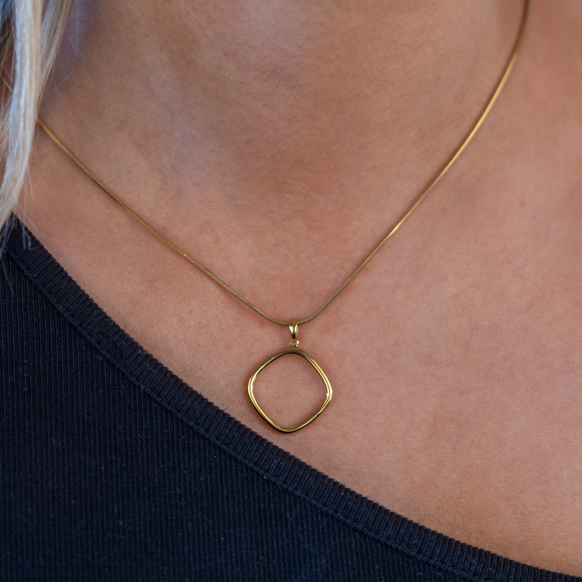 Minimalist gold vermeil pendant necklace worn by model. The pendant is a geometric ring shape with rounded edges.