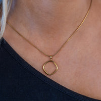 Minimalist gold vermeil pendant necklace worn by model. The pendant is a geometric ring shape with rounded edges.