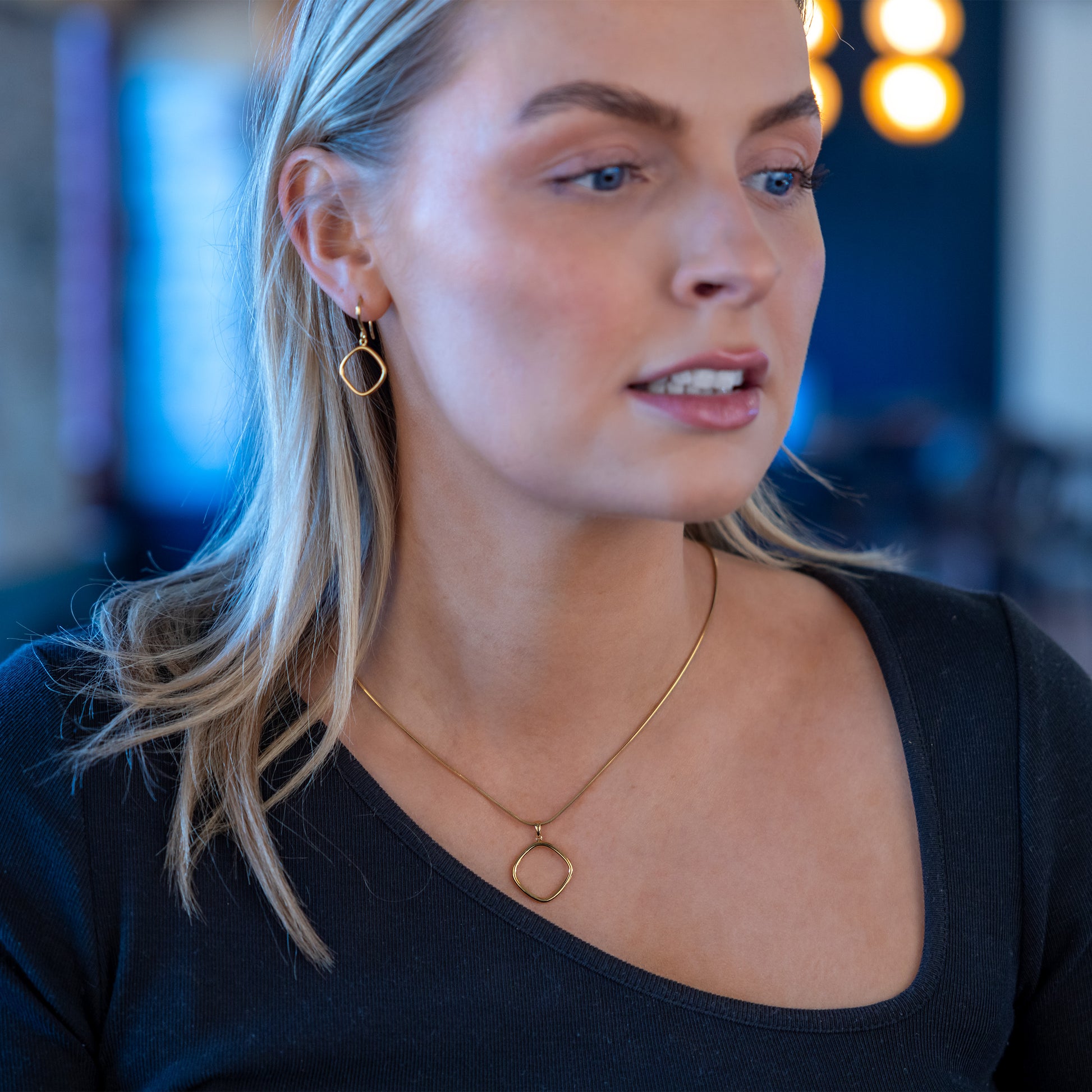 Model wearing matching earring and pendant necklace set. The set is gold vermeil, simple rounded edge, geometric shaped pendant. Tarnish free