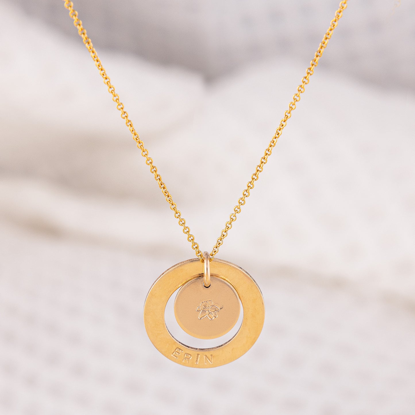 Personalised 14-ct gold- filled necklace. The Dooey necklace's pendant is a smooth textured halo, hand stamped with the wearers name. Inside the halo tehre is a smaller gold disc that has a birthflower stamped in the centre. Handmade in Ireland!