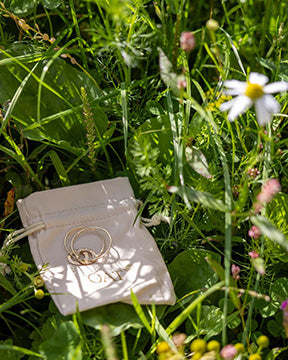 A pair of personalised earrings resting on a branded jewellery bag.