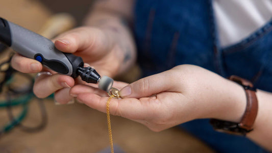 Jeweller polishing a gold fill pendant with a Dremel 
