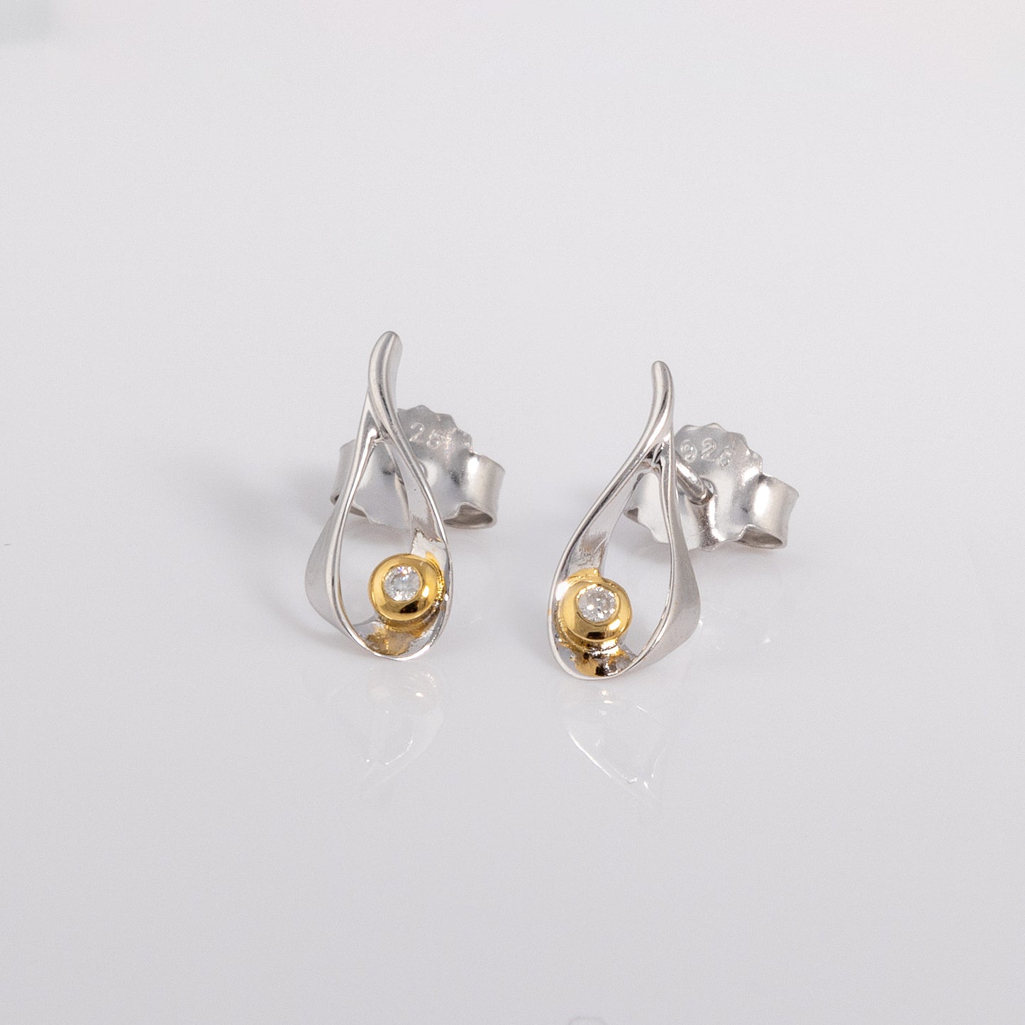 Stud earrings with a butterfly clasp. the earring  is rhodium plated silver with gold vermeil detail surrounding one set diamond. 