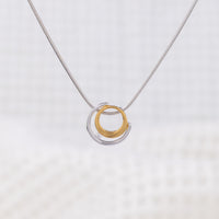 Rhodium plated silver and gold vermeil pendant with a white cubic zirconia detail. The pednant design is a gold circle surrounded by a silver semi circle, the white cubic zirconia placed between the two. The pendant is on a rhodium plated silver, snake chain.