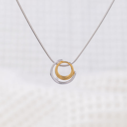 Rhodium plated silver and gold vermeil pendant with a white cubic zirconia detail. The pednant design is a gold circle surrounded by a silver semi circle, the white cubic zirconia placed between the two. The pendant is on a rhodium plated silver, snake chain.