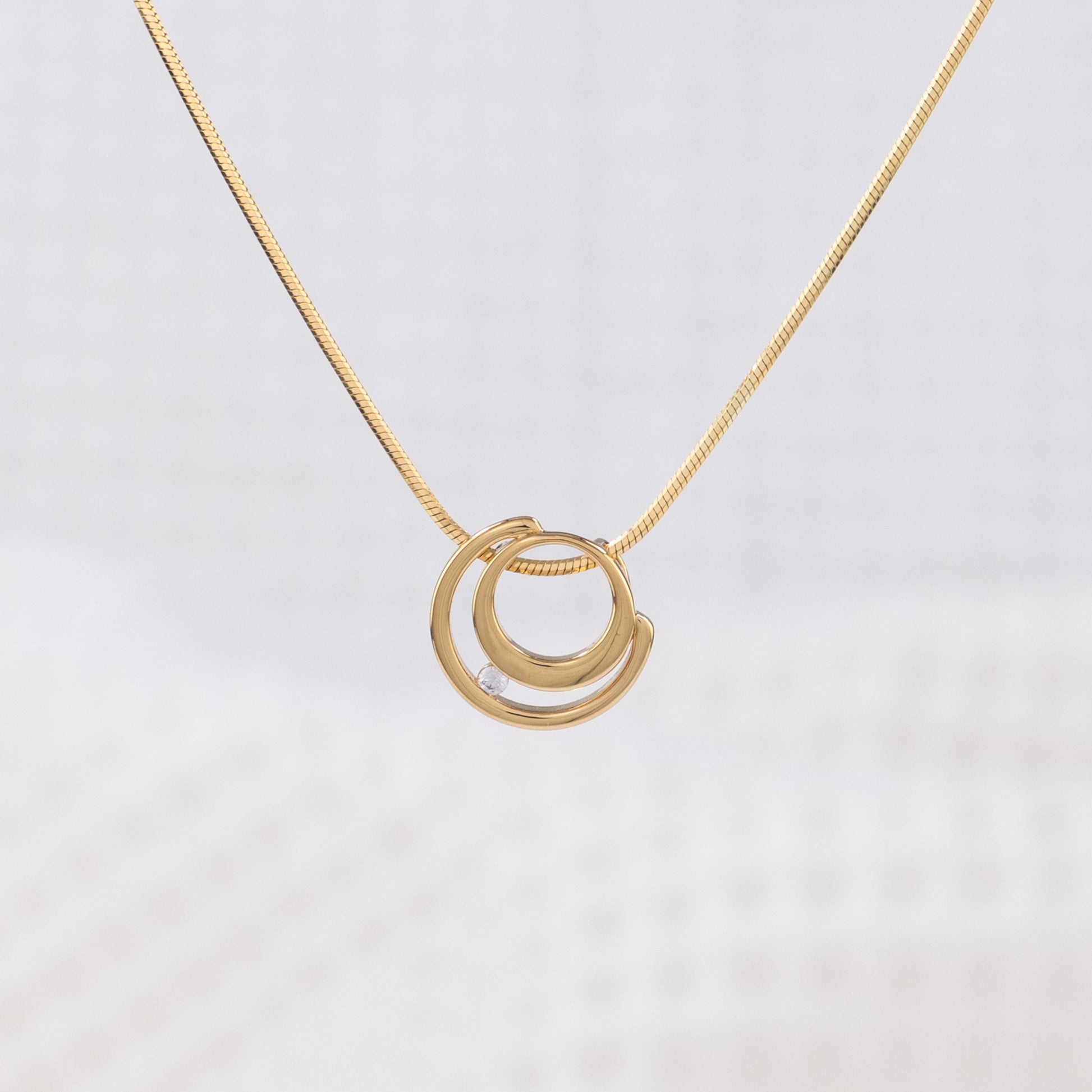 Gold vermeil circle shaped pendant necklace with white cubic zirconia detail on a delicate snake chain