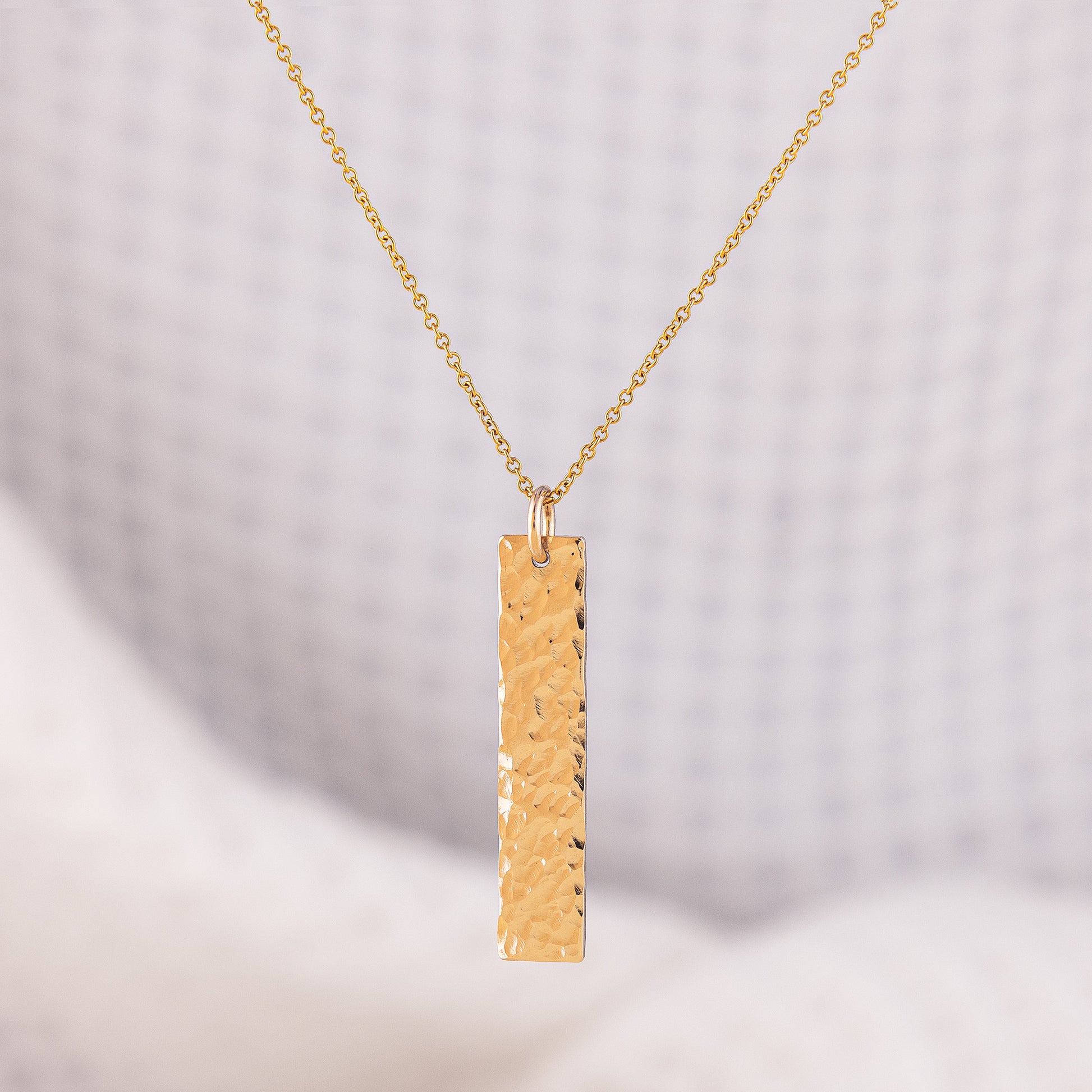 A hammered bar pendant necklace. The pendant is 14ct gold fill and has a hammered finish, it can be customised with a hand stamped word/ name of your choice. The bar is sparkly and hangs upon a fine chain