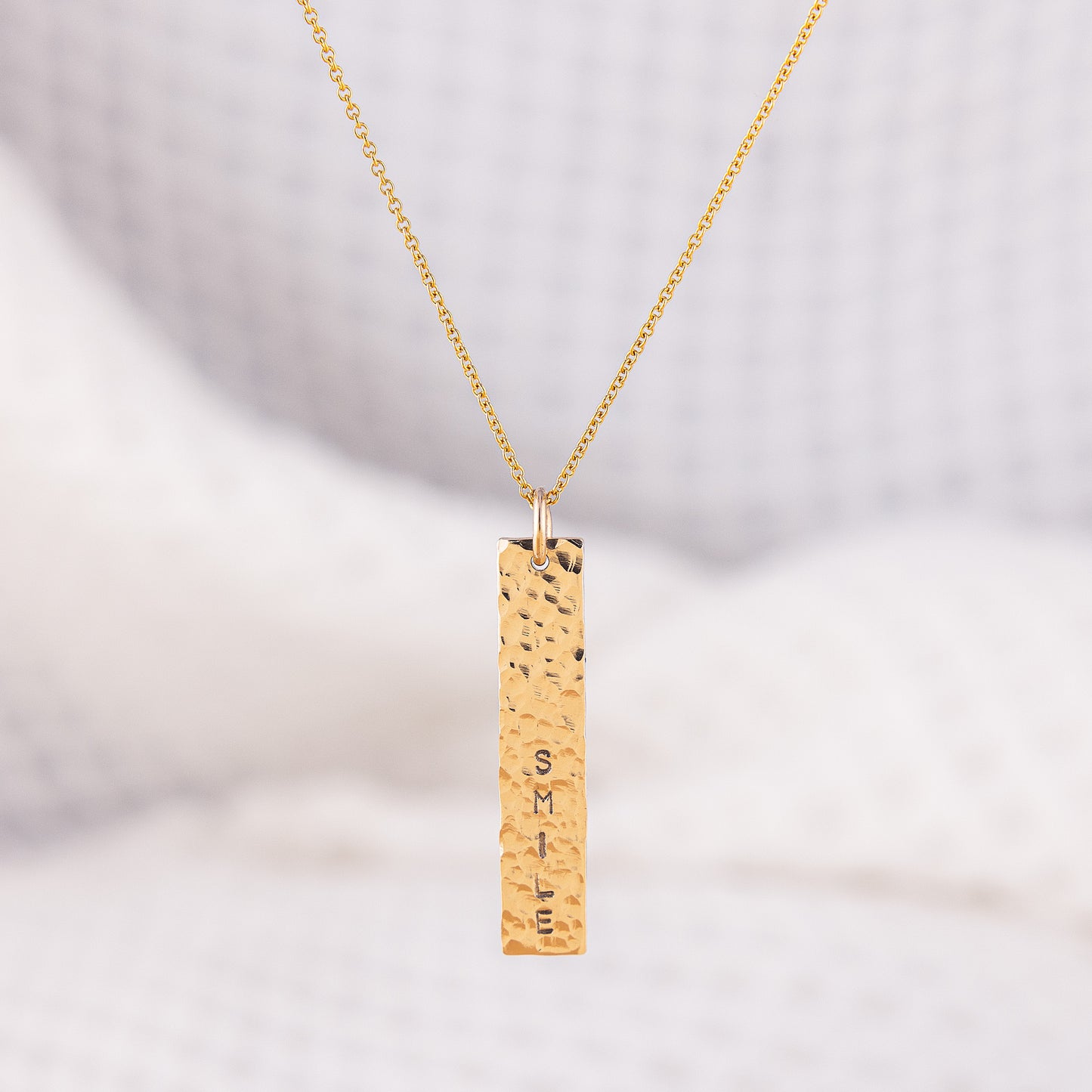 A unique, 14ct gold-filled, hammered bar pendant necklace. The pendant has a sparkly, textured finished and is stamped with a custom word of your choice. On a dainty 16 inch chain with 2 inch extension.