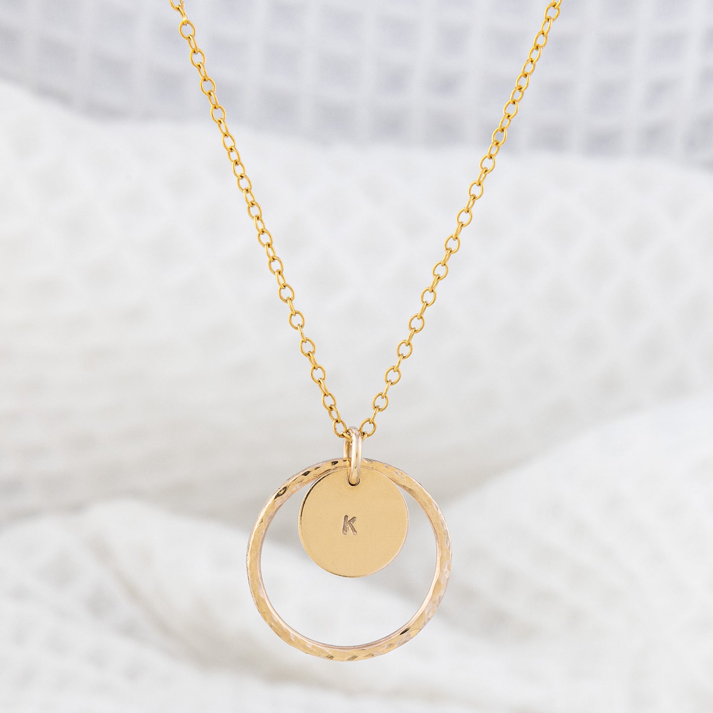 14ct gold-filled personalised necklace, tarnish resistant and hypoallergenic. The necklace features a hammered, thin gold ring surrounding a small smooth gold disc hand stamped with an initial.