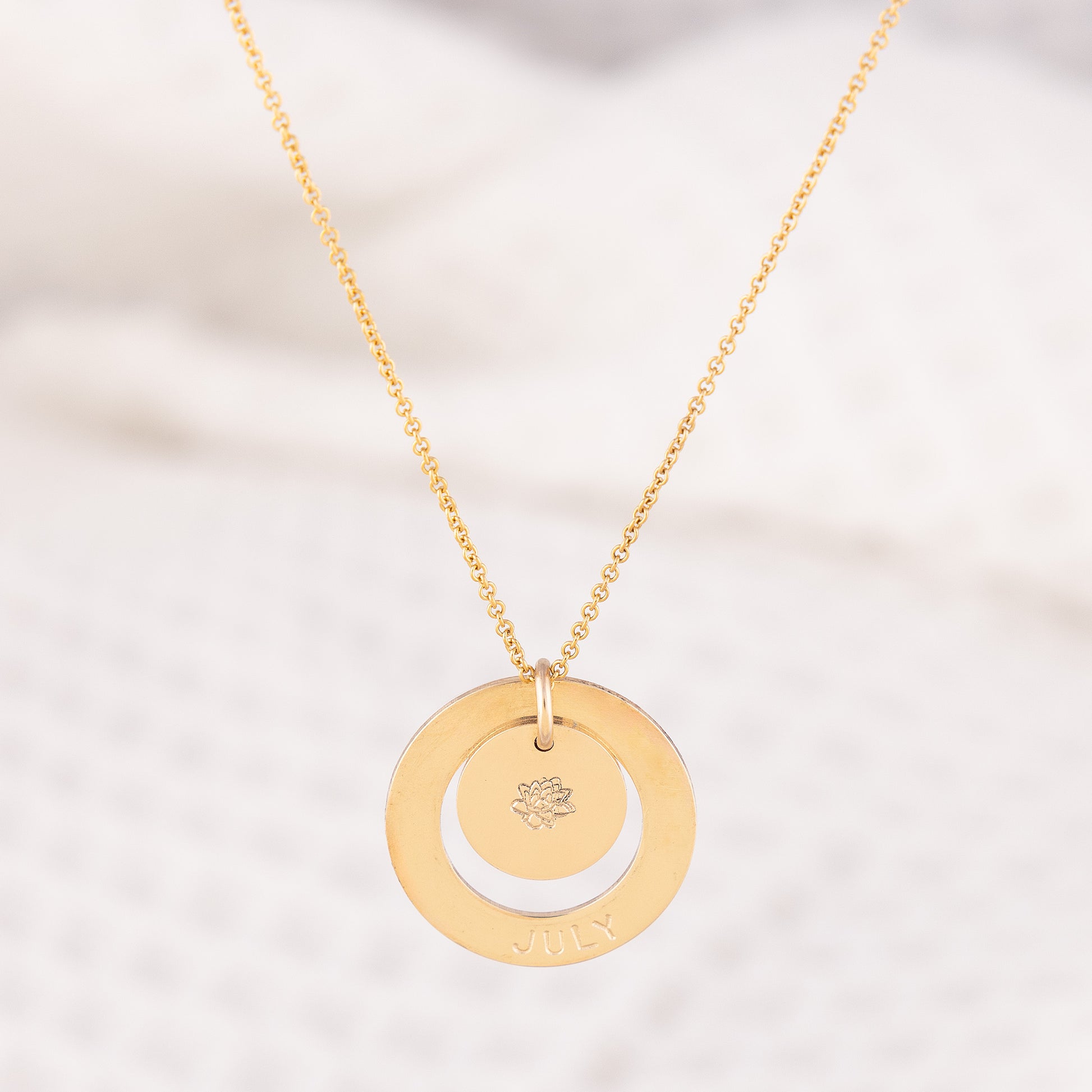 OAT Jewellerys grgeous Dooey personalised necklace. The 14ct gold-fill necklace has a halo pendant, stamped with a birth month with a pendant inside stamped with the matching birthflower. A dainty everyday necklace, hypoallergenic and a beautiful gift for a new Mom!